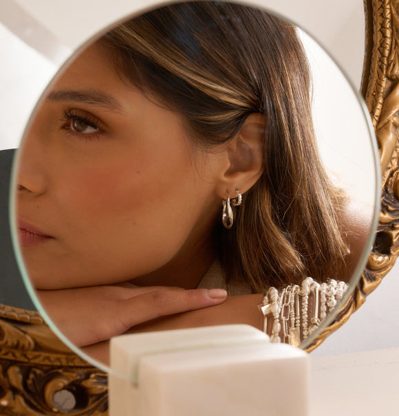 Woman looking into the mirror wearing 2 sets of ChloBo earrings